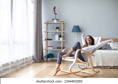 Happy woman resting comfortably sitting on modern chair in the living room at home. Lifestyle.