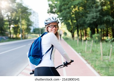 Happy woman riding bike on city street. Road with bicycle path. Cyclists
