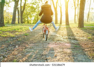 Happy Woman Riding Vintage Red Italian Style Bicycle With Her Legs In The Air - Girl Having Fun In Park Outdoor With Back Sun Light - Freedom Concept  - Warm  Filter With Focus On Bike Wheel