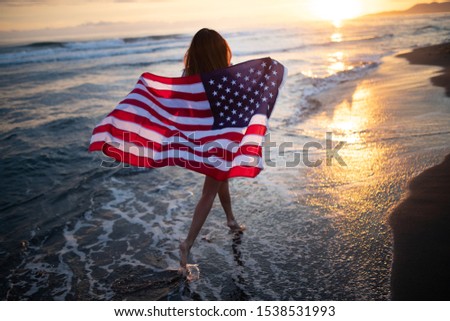 Happy woman running on beach while celebrateing independence day and enjoying freedom in USA
