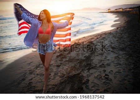 Happy woman running on beach while celebrateing independence day and enjoying freedom in USA