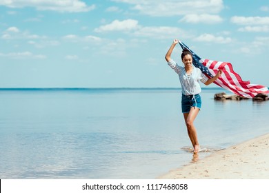 happy woman running in sea water with american flag, independence day concept - Powered by Shutterstock