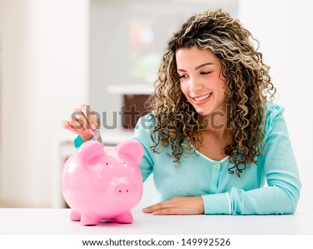 Happy woman saving money in a piggybank 