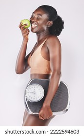 Happy Woman, Scale And Apple For Losing Weight, Healthy Diet And Fitness Results, Progress And Exercise Motivation On Studio Background. Black Model Eating Fruits, Sports Nutrition And Body Wellness