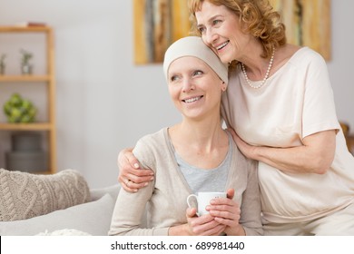 Happy woman with scarf struggling with illness with her mom's help - Shutterstock ID 689981440
