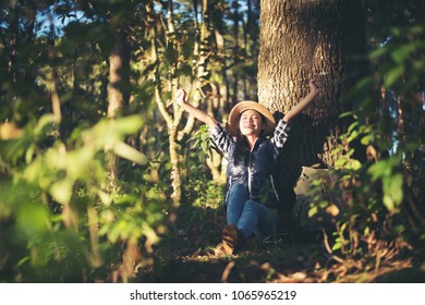 Happy woman seated on the ground in the forest  - Shutterstock ID 1065965219