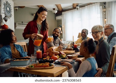 Happy woman serving drinks to her multigeneration family while gathering for lunch on Thanksgiving at dining table. - Powered by Shutterstock