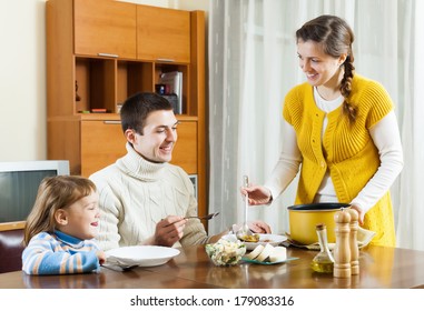 Happy Woman Serving Soup For Family In Home