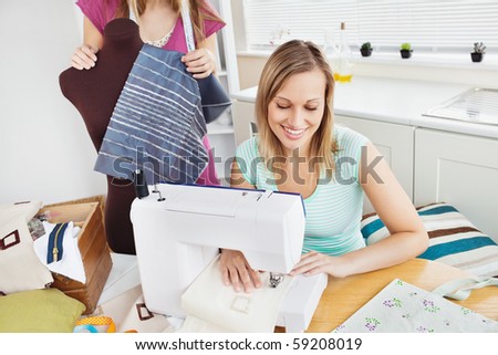 Happy woman sewing at home in the kitchen with her friend