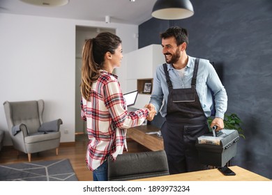 Happy woman shaking hands with repairman. Home interior.