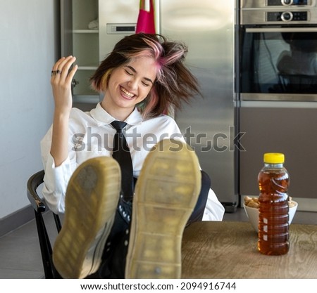 happy woman shaking her head from side to side, reclining in her chair with her feet on the worktop, horizontal indoor picture