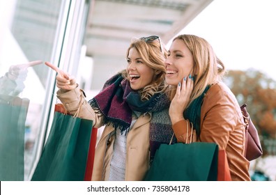 Happy Woman With Shopping Bags Pointing Finger In The Shop Window.