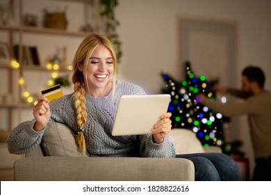 Happy Woman Shopping Online On Christmas, Using Digital Tablet And Credit Card, Xmas Sales Concept, Copy Space. Smiling Young Lady With Pad Sitting At Home And Buying Xmas Gifts For Her Family