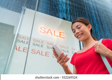 Happy Woman Shopping Sale Event Using Mobile Phone App At Store Front Mall Outside. Asian Girl Spending Online With Smartphone.