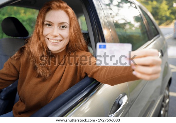 Happy\
woman showing car license after new car\
purchase