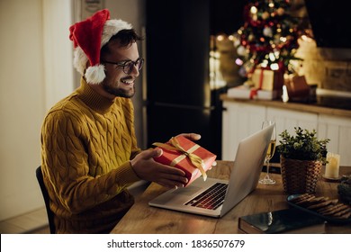 Happy Woman Showing A Gift While Having Video Call Over Laptop On Christmas Eve At Home. 