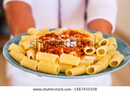 happy woman showing her pasta she cooked 5 minutes ago - adult or senior cook at home in the kitchen food with meat - preparing chef italian food with colors and carbos