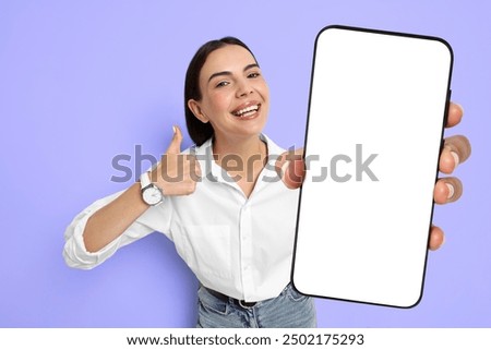 Happy woman showing mobile phone with blank screen on blue violet background. Mockup for design