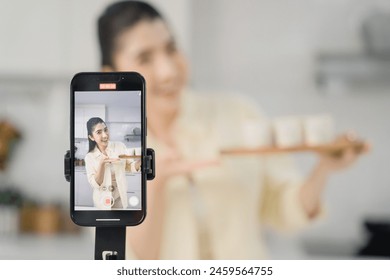 Happy woman showing off freshly baked cakes while video calling in a modern kitchen setting. - Powered by Shutterstock