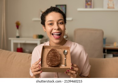 Happy Woman Showing Stuffed Chocolate Easter Egg At Home.