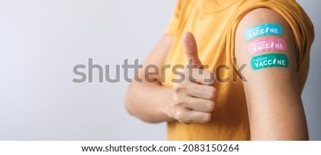 Happy woman showing Thumb sign with bandage after receiving covid 19 vaccine. Vaccination, herd immunity, side effect, booster dose, vaccine passport and Coronavirus pandemic