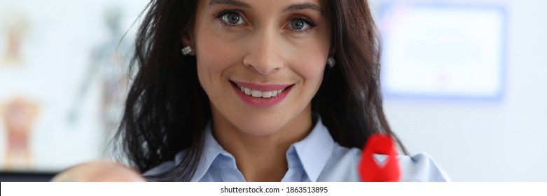 Happy Woman Shows Breast Implant And Red Ribbon. Way Out Critical Situation An Oncologically Ill Woman. Features Implantation After Breast Removal. Formation For Rehabilitation Treatment