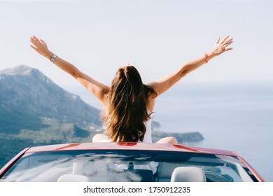 Happy woman sits in a red convertible car with a beautiful view - Powered by Shutterstock