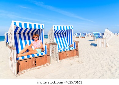 Happy woman sitting in beach chair and enjoying summer time, Kampen, Sylt island, Germany