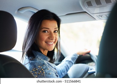 Happy woman sitting in a car and looking back