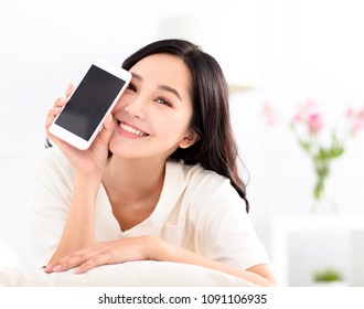 Happy Woman Sitting On Couch And Showing The Phone