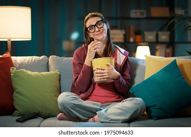 Happy woman sitting on the sofa and watching her favorite romatic movie on television