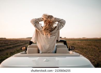 Happy woman sitting in white convertible car with beautiful view