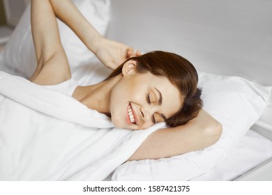 Happy Woman Sleeping On A Pillow In Bed And Smiling