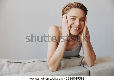 Happy woman smile lying at home on the couch relaxing on a weekend at home with a short haircut hair without filters on a white background, free copy space