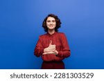 happy woman smiling at camera and showing help gesture on sign language isolated on blue