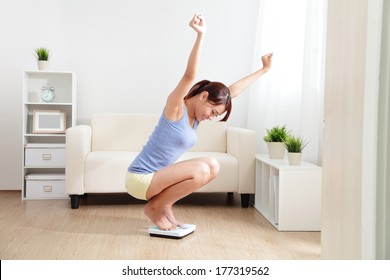 Happy Woman Smiling On Weighing Scales At Home, Asian