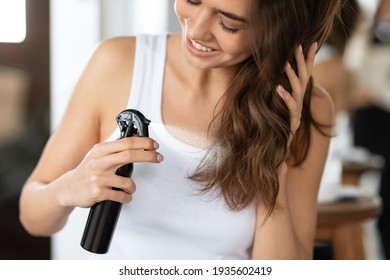 Happy Woman Spraying Hairspray Styling Wavy Hair In Bathroom, Cropped