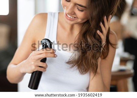 Happy Woman Spraying Hairspray Styling Wavy Hair In Bathroom, Cropped