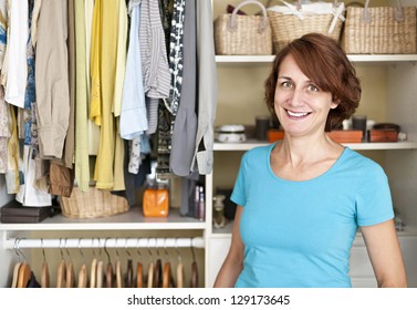 Happy woman standing in front of custom organized closet at home