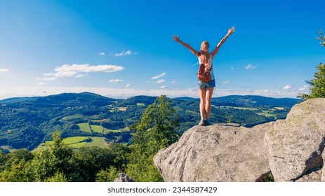 Happy woman standing on cliff,  Morvan in France- Travel, freedom, achievement concept