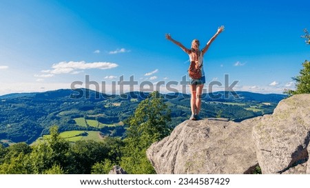 Happy woman standing on cliff,  Morvan in France- Travel, freedom, achievement concept
