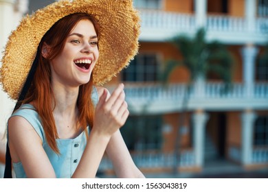 A happy woman in a straw hat smiles and a sundress building in the background of a column of baluster                            - Shutterstock ID 1563043819