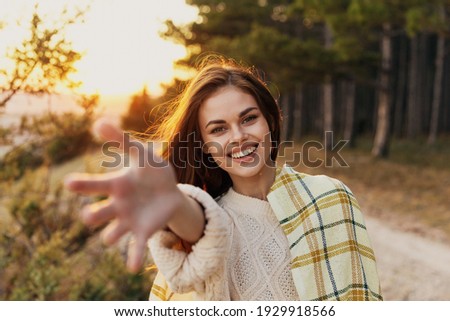 happy woman stretches her hand forward on nature near green bushes