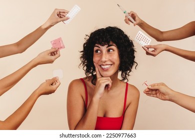 Happy woman in studio with hands offering birth control options. Woman smiles as she thinks about what choice to make for her body, she is deciding between hormonal and non-hormonal contraception.