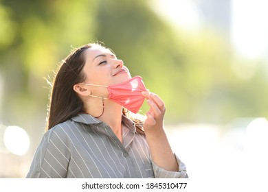 Happy Woman Taking Off Mask Breathing Fresh Air Outdoors In A Park