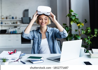 happy woman taking off vr headset and looking at laptop