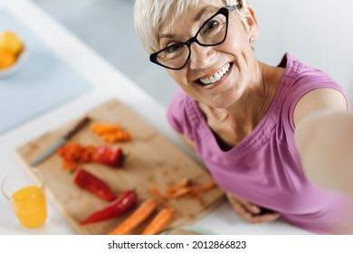 Happy Woman Taking A Self Portrait Photography While Cooking Lunch In The Kitchen And Looking At Camera.