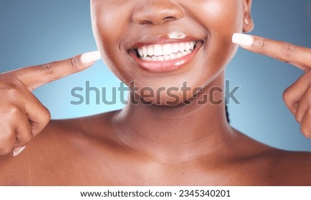 Happy woman, teeth and pointing in dental cleaning, hygiene or treatment against a blue studio background. Closeup of female person mouth in tooth whitening, oral and gum care with big smile