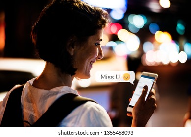 Happy woman texting while walking at night