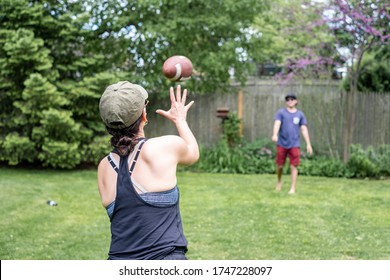 Happy Woman Throwing A Football In The Backyard, Playing Catch With Her Boyfriend